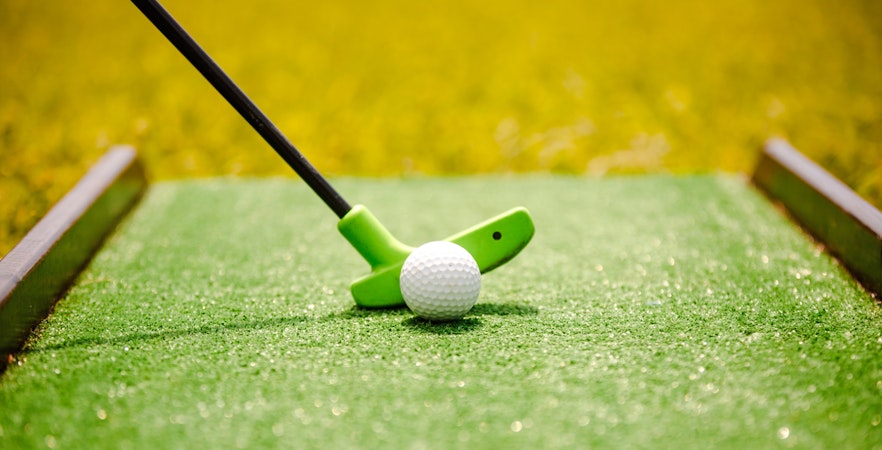 Mini golf putter and ball on green course.