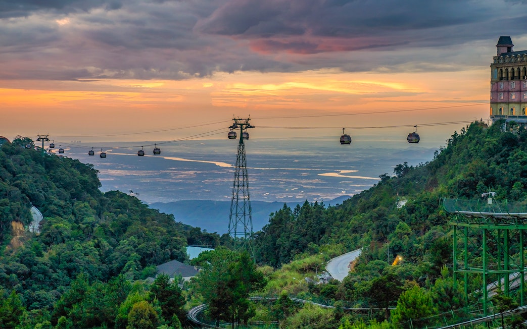 Cable cars over lush hills at sunset in Ba Na Hills, Vietnam.