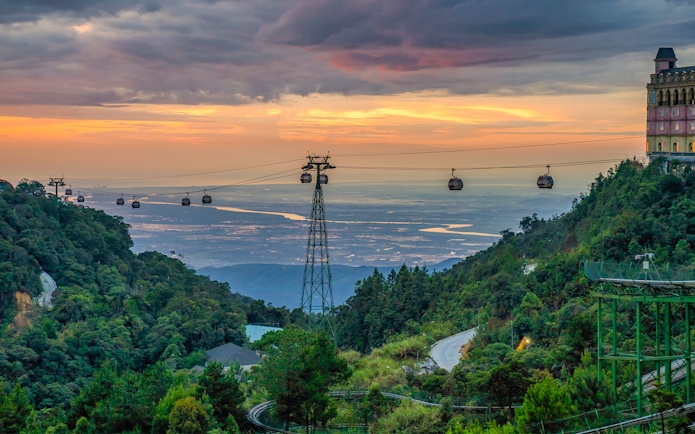 Cable cars over lush hills at sunset in Ba Na Hills, Vietnam.