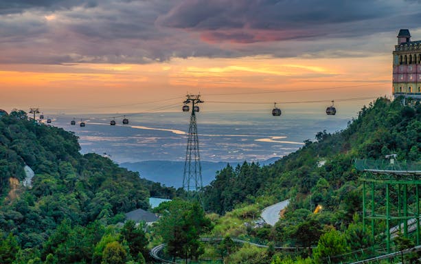 Cable cars over lush hills at sunset in Ba Na Hills, Vietnam.