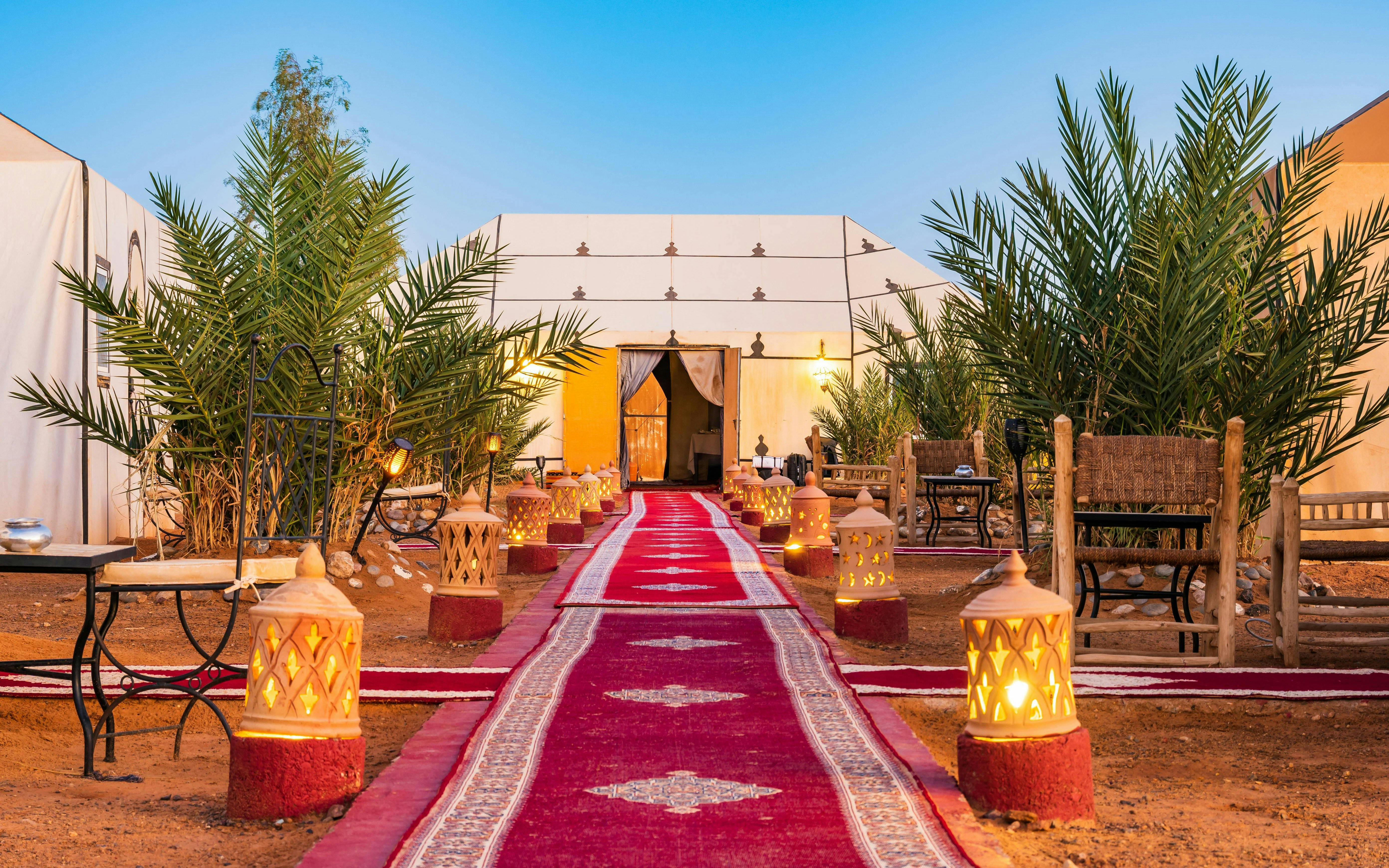 Luxury tent camp with fire lamps and red carpet at Erg Chebbi desert.