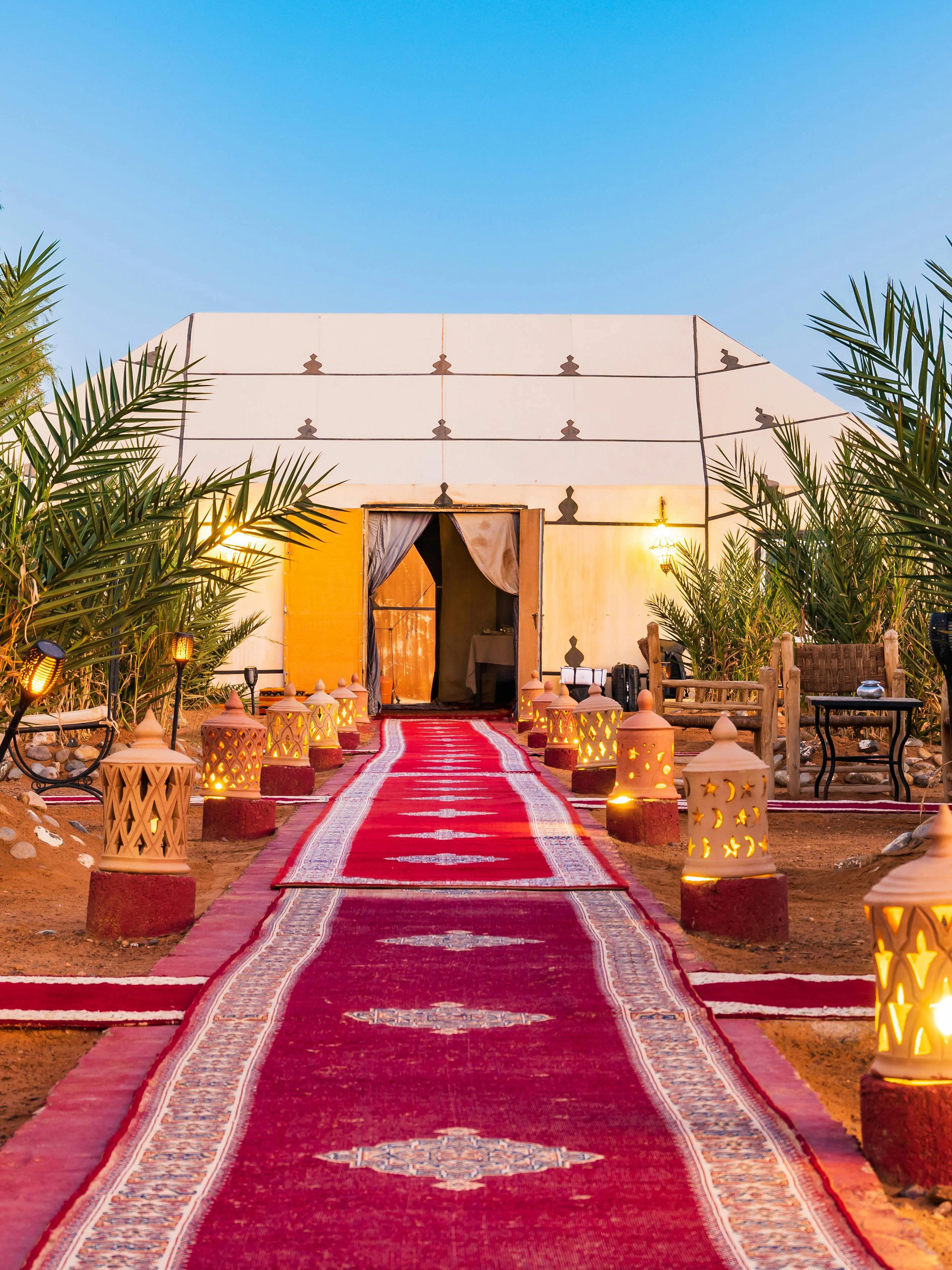 Luxury tent camp with fire lamps and red carpet at Erg Chebbi desert.