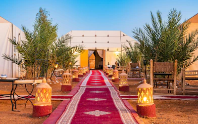 Luxury tent camp with fire lamps and red carpet at Erg Chebbi desert.