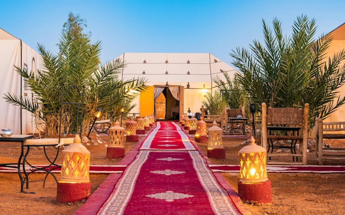 Luxury tent camp with fire lamps and red carpet at Erg Chebbi desert.