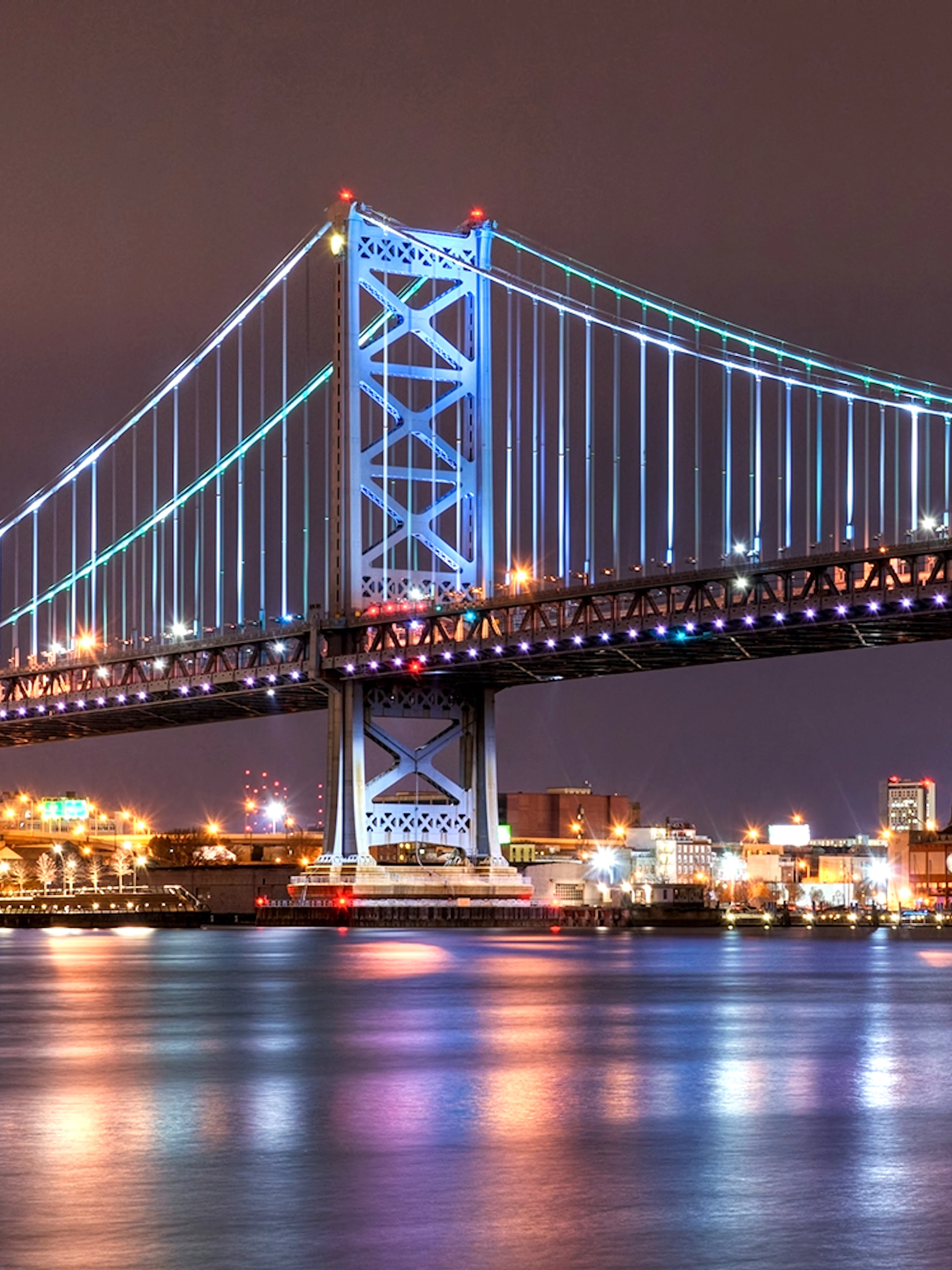 Ben Franklin Bridge illuminated at night over the Delaware River in Philadelphia.