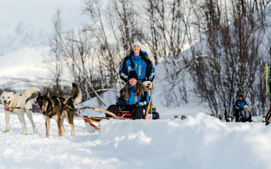 Guests dogsledding through snowy landscape in Tromso.