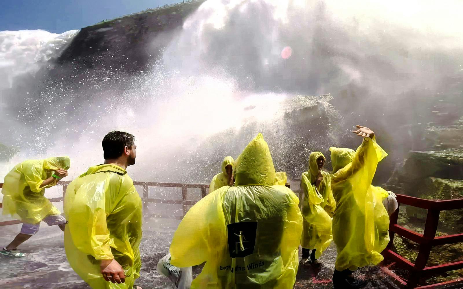 Visitors in yellow ponchos at Cave of the Winds, Niagara Falls, experiencing mist and spray.