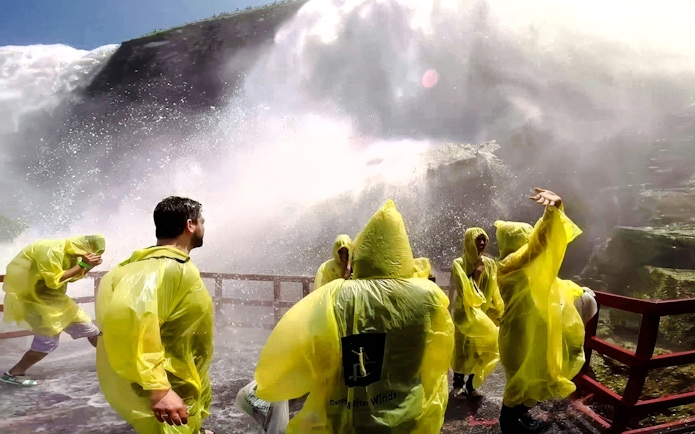 Visitors in yellow ponchos at Cave of the Winds, Niagara Falls, experiencing mist and spray.