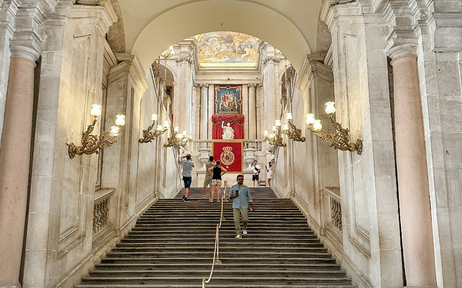 Grand staircase with ornate lamps in the Royal Palace of Madrid.