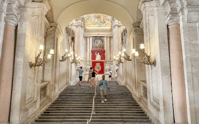 Grand staircase with ornate lamps in the Royal Palace of Madrid.