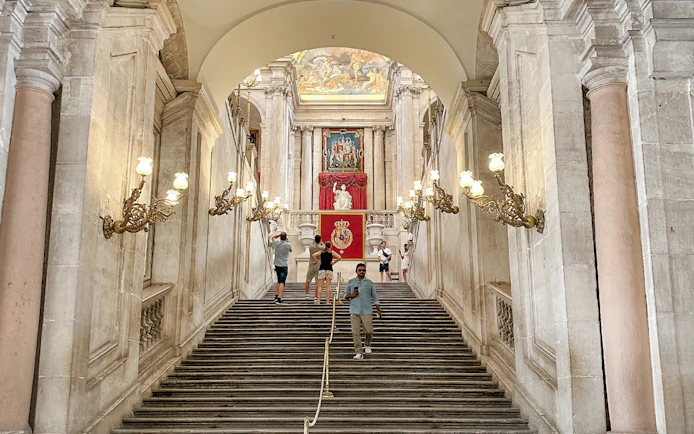 Grand staircase with ornate lamps in the Royal Palace of Madrid.