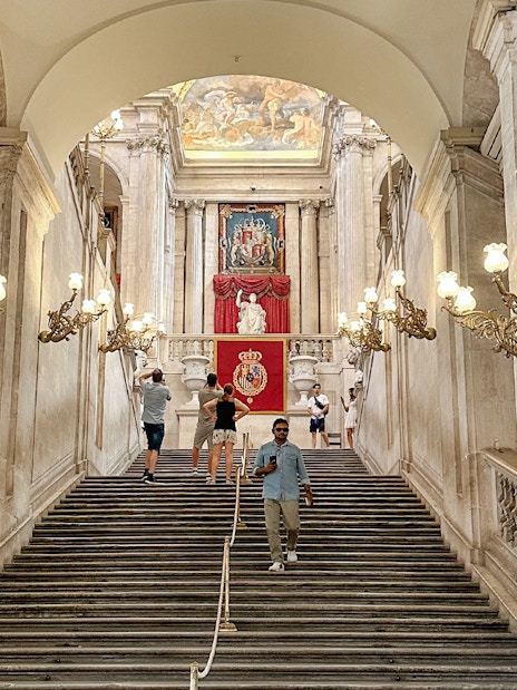 Grand staircase with ornate lamps in the Royal Palace of Madrid.
