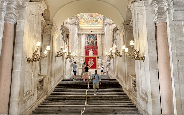 Grand staircase with ornate lamps in the Royal Palace of Madrid.