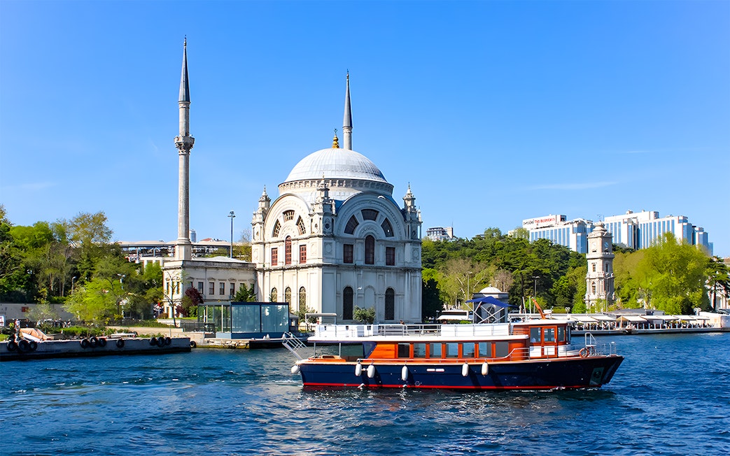 Bosphorus cruise boat passing Dolmabahçe Mosque in Istanbul.