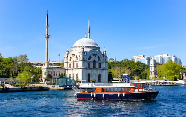 Bosphorus cruise boat passing Dolmabahçe Mosque in Istanbul.