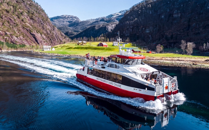 Cruise boat on Mostraumen Fjord near Bergen with scenic mountain views.