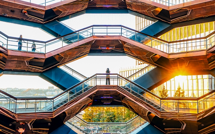 Vessel structure in New York City with visitors on staircases at sunset.