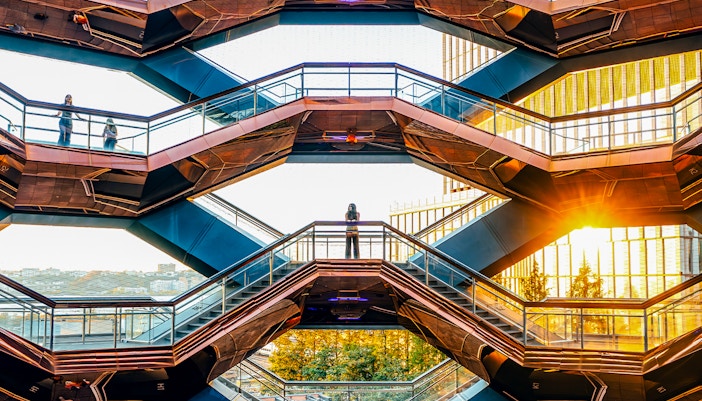 Vessel structure in New York City with visitors on staircases at sunset.
