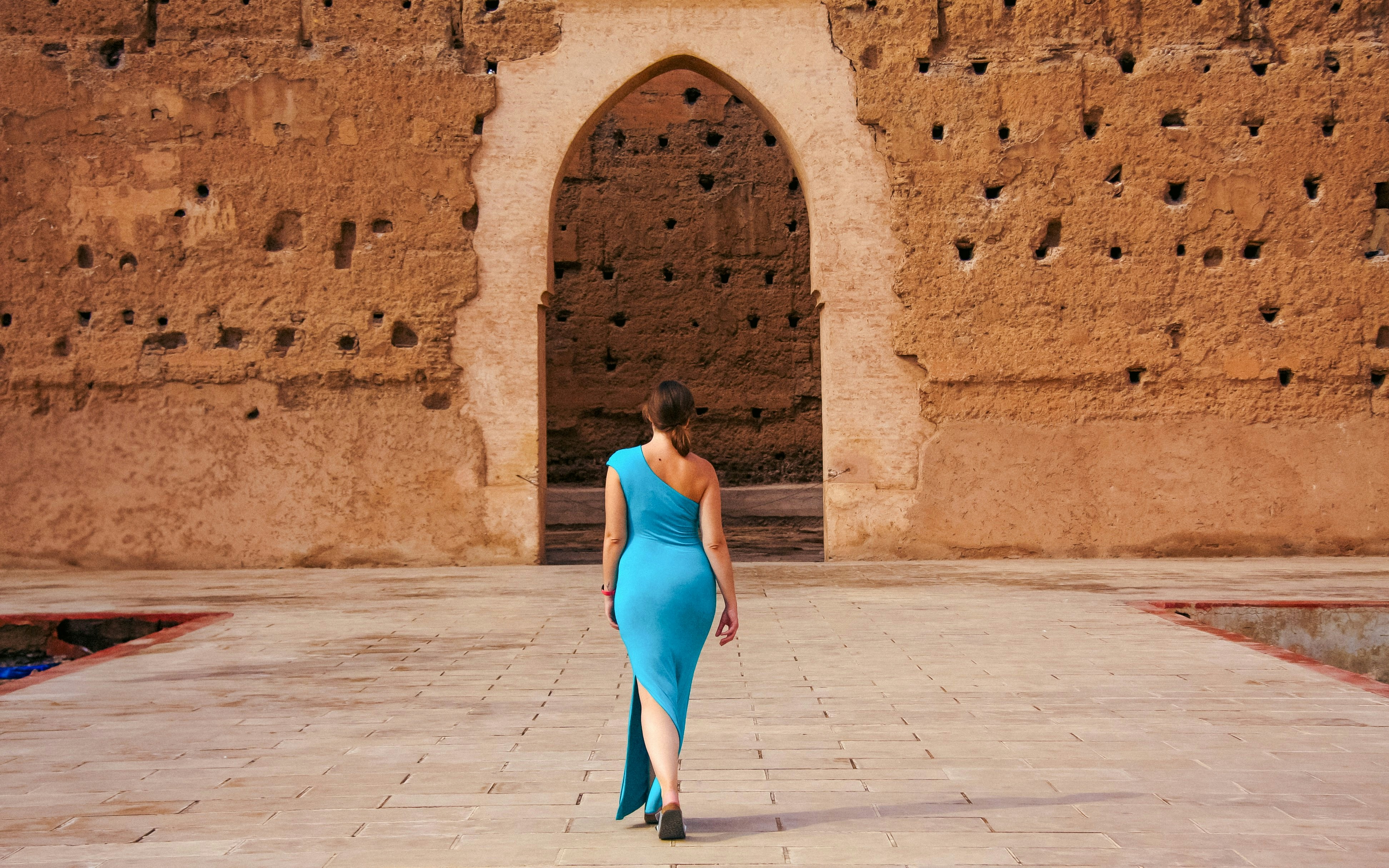 Person walking towards archway at El Badi Palace, Marrakech.