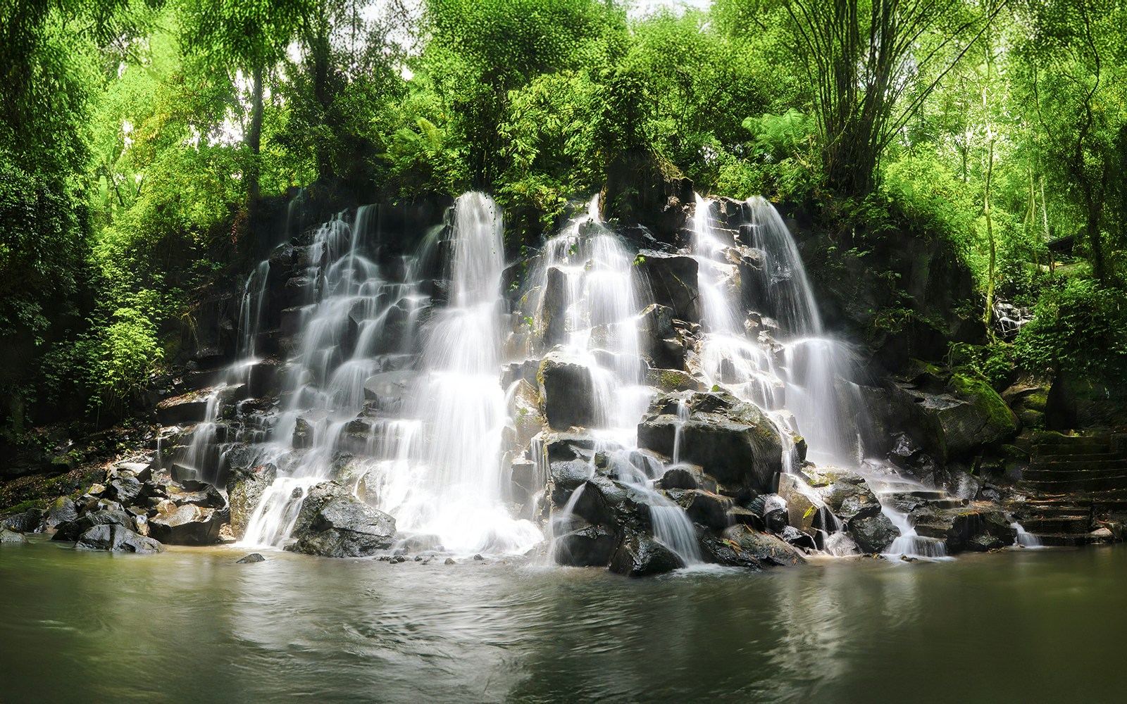 Kanto Lampo Waterfall cascading over rocks surrounded by lush greenery in Ubud, Bali.