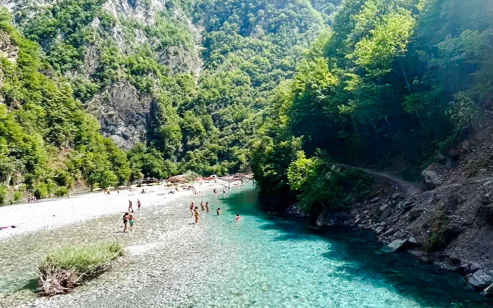 Guests swimming in the clear Shala River surrounded by lush green cliffs.