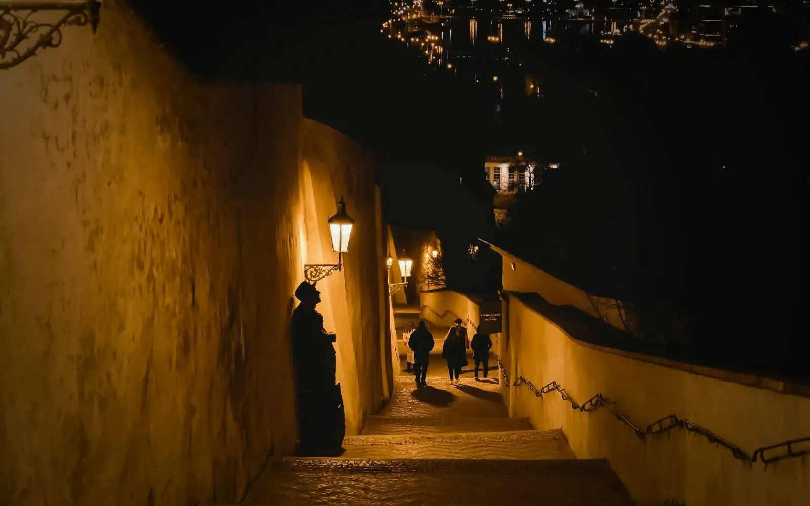 Prague Castle night tour with lit pathway and distant city lights.
