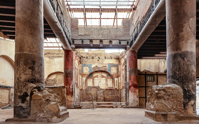 Interior of the College of the Augustales in Herculaneum with ancient frescoes and columns.