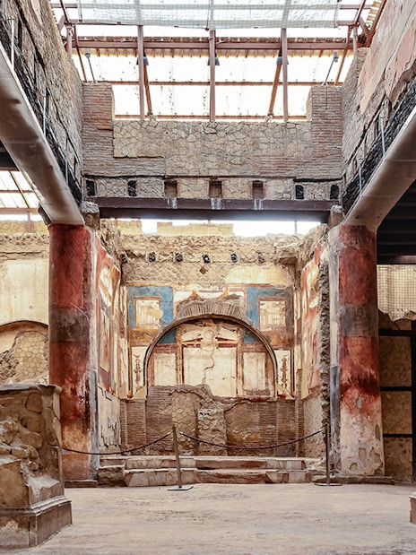Interior of the College of the Augustales in Herculaneum with ancient frescoes and columns.