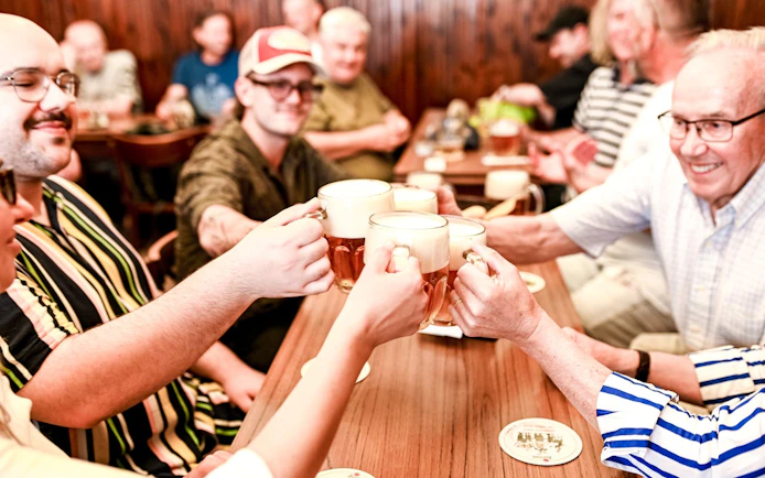 People toasting with beer mugs during a Prague food tour.