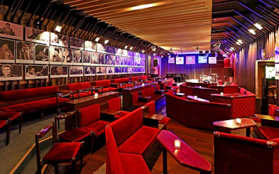 Interior of Reduta Jazz Club with red seating, stage, and musician portraits on walls.