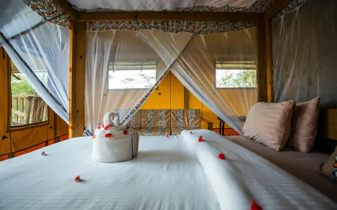 Safari tent interior with bed and decorative towels, part of the 5-Day Tarangire, Serengeti, Ngorongoro tour.