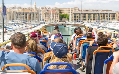People on a hop-on hop-off bus tour in Marseille, viewing the Old Port.