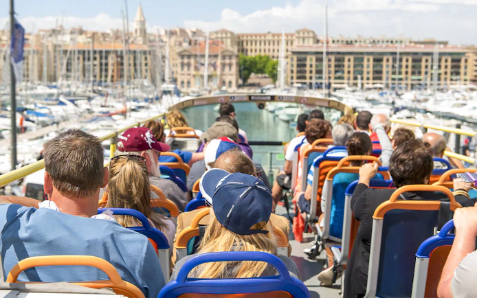 People on a hop-on hop-off bus tour in Marseille, viewing the Old Port.