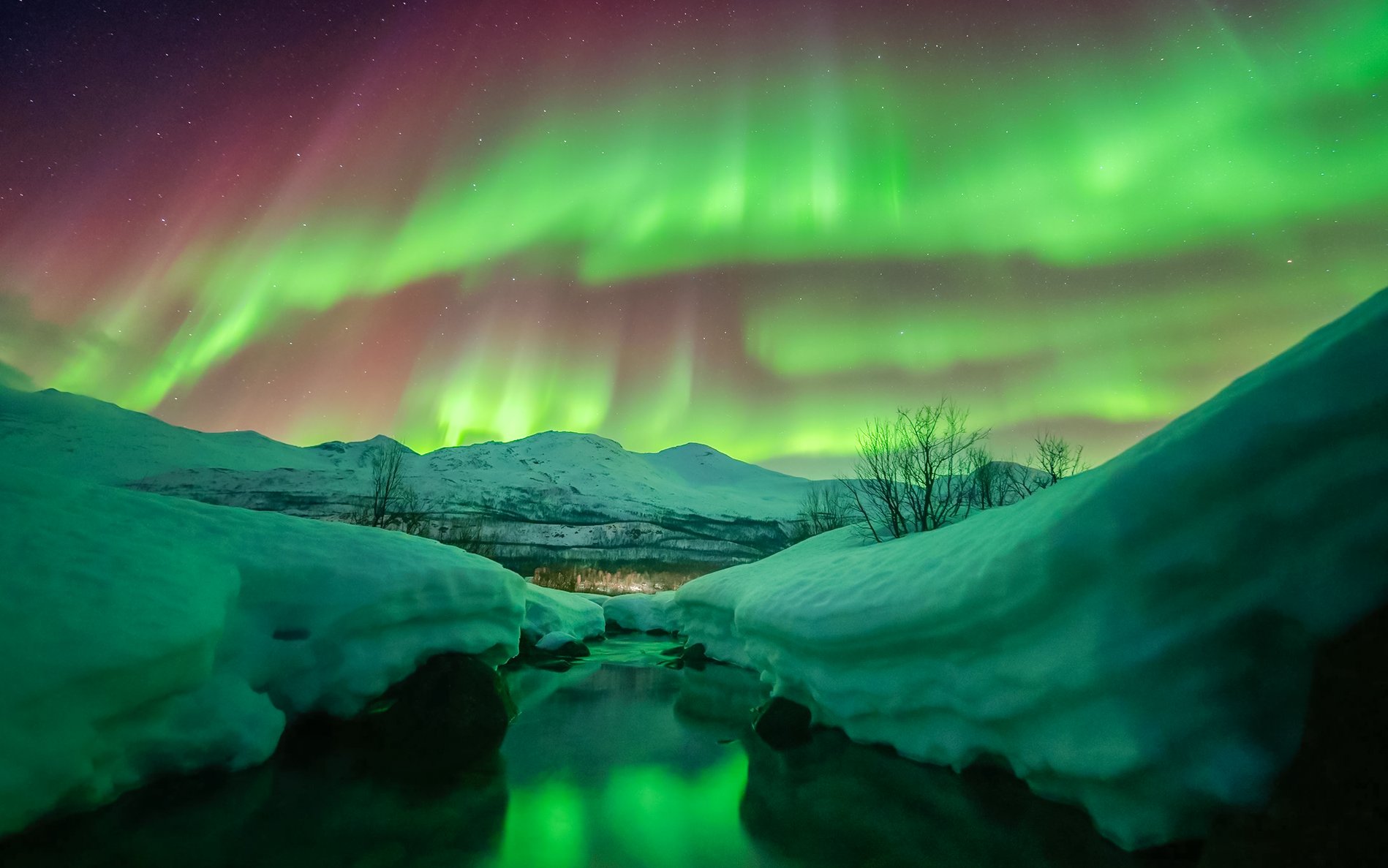 Northern lights over snowy landscape in Tromso, Norway.