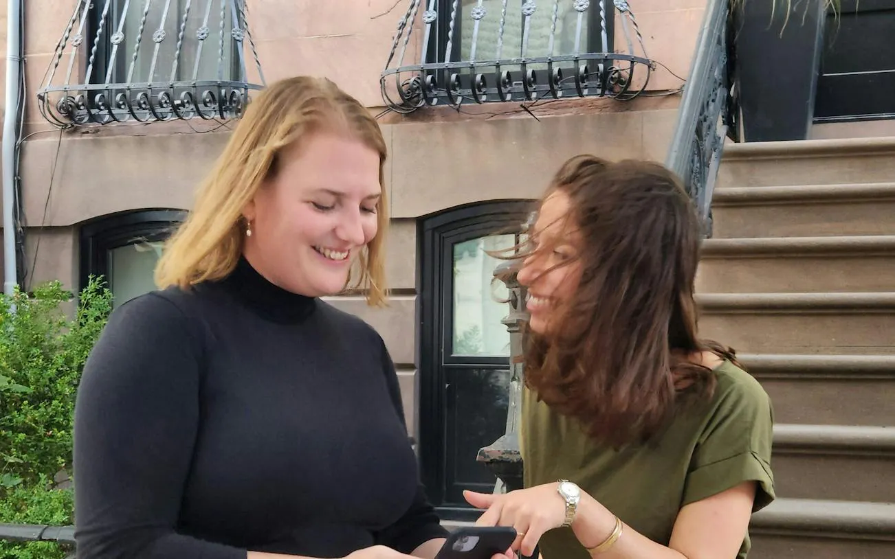 Women enjoying a self-guided city exploration game in front of a New York brownstone.
