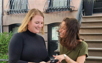 Women enjoying a self-guided city exploration game in front of a New York brownstone.
