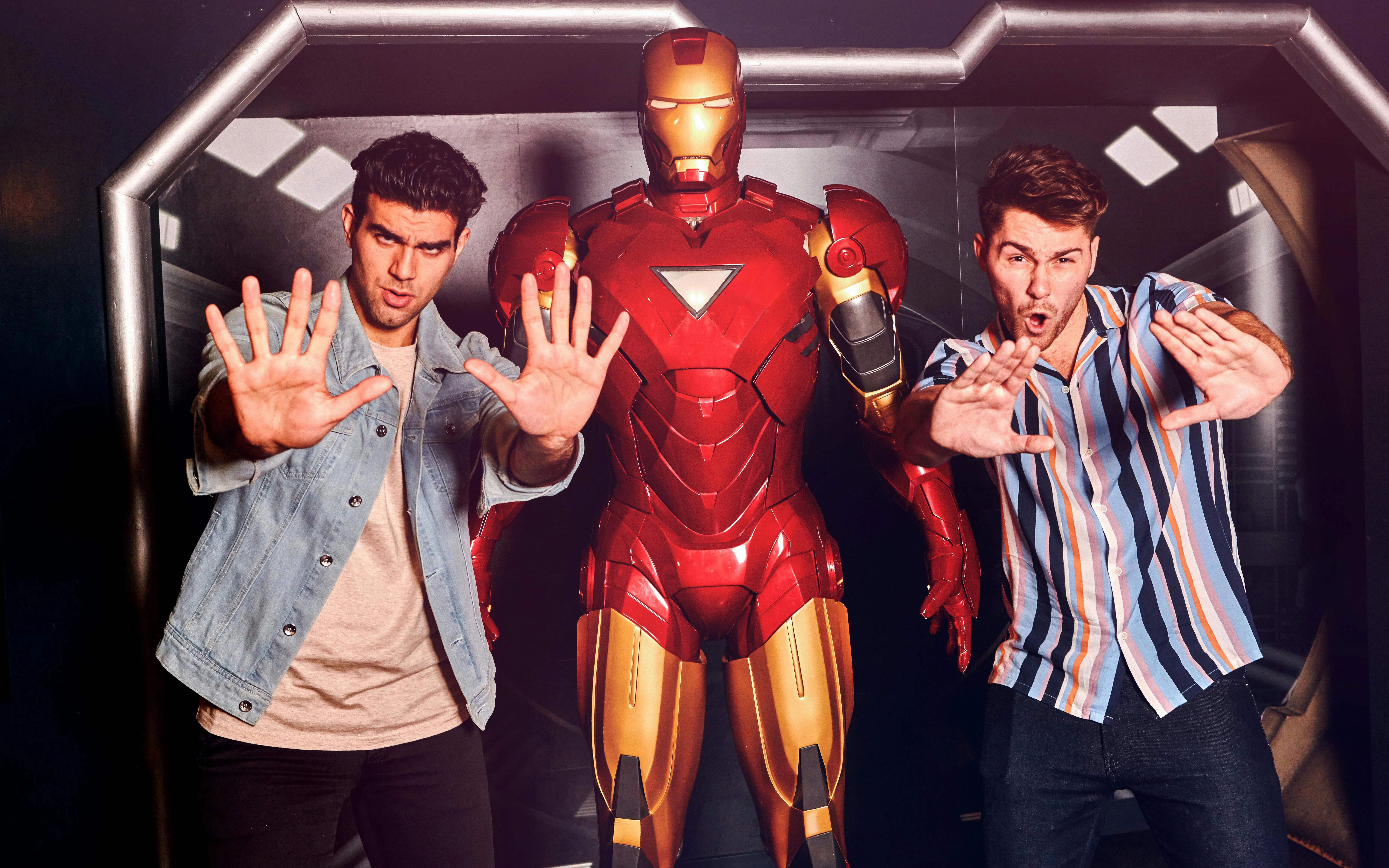Visitors posing with Iron Man statue at Marvel Hall of Heroes exhibit.
