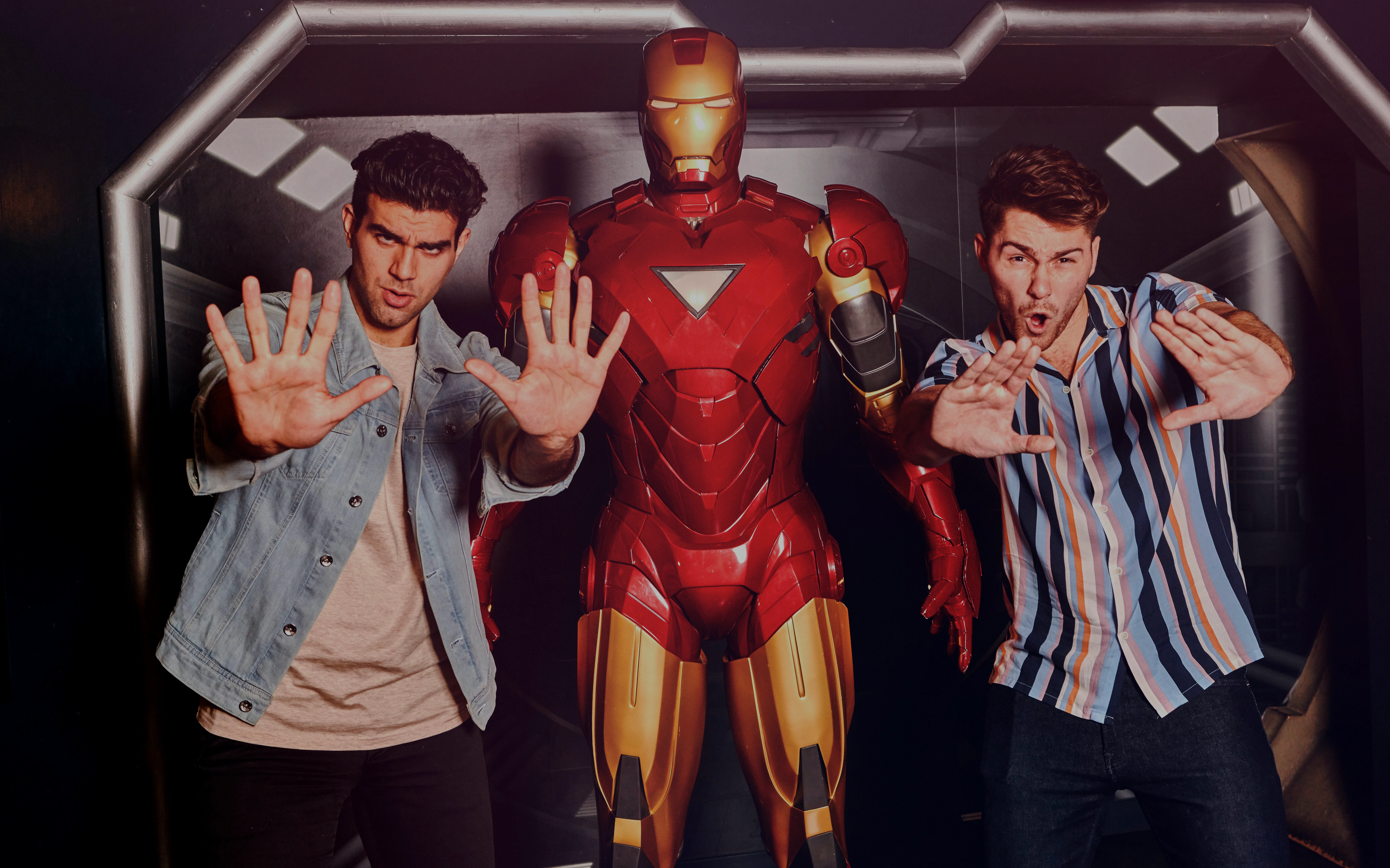 Visitors posing with Iron Man statue at Marvel Hall of Heroes exhibit.