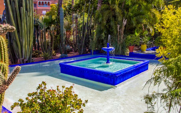 Majorelle Garden fountain surrounded by cacti and greenery in Marrakesh.