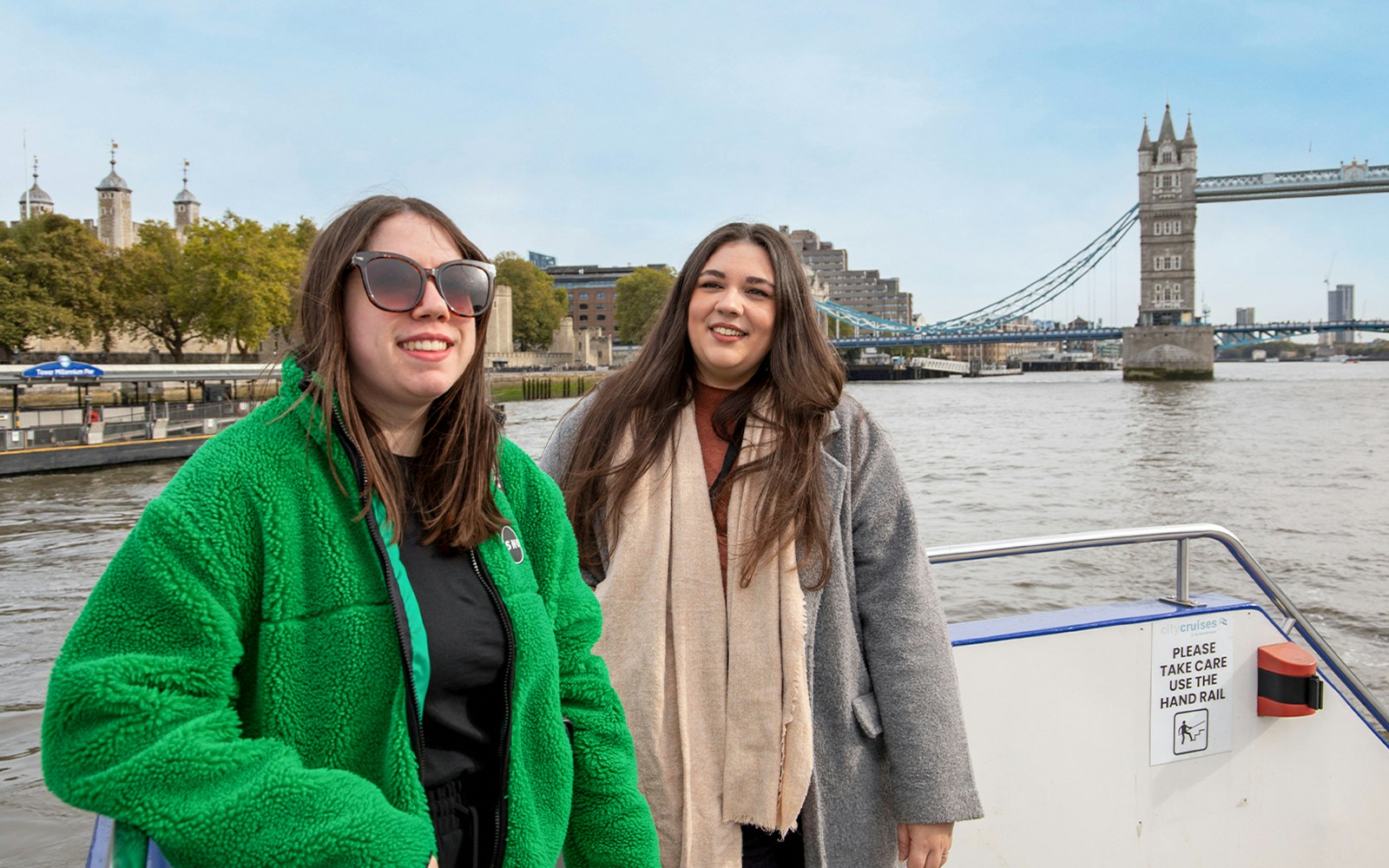 Women enjoying a Thames River afternoon cruise with Tower Bridge in the background.