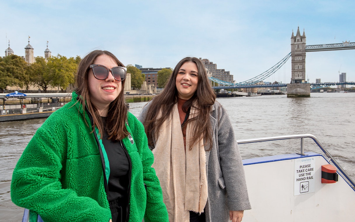 Women enjoying a Thames River afternoon cruise with Tower Bridge in the background.