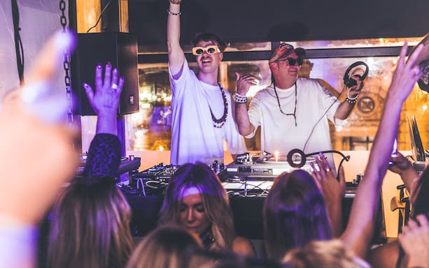 DJs performing at Es Paradis nightclub in Ibiza with a lively crowd.