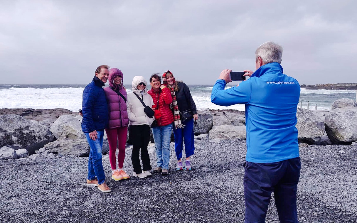 Group posing for a photo on a rocky shore during a guided tour in the Burren.