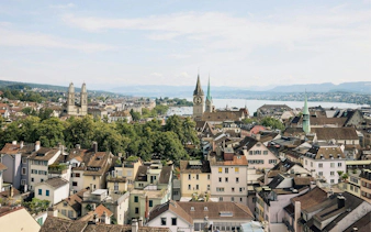 Panoramic view of Zurich's old town with historic churches and Lake Zurich in the background.