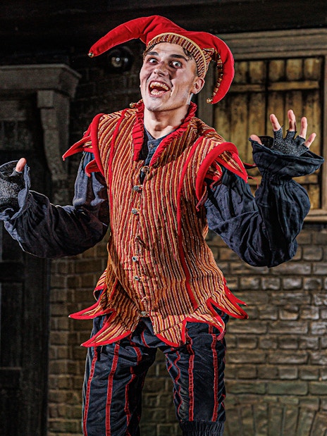 Performer in jester costume at London Dungeon VIP experience.