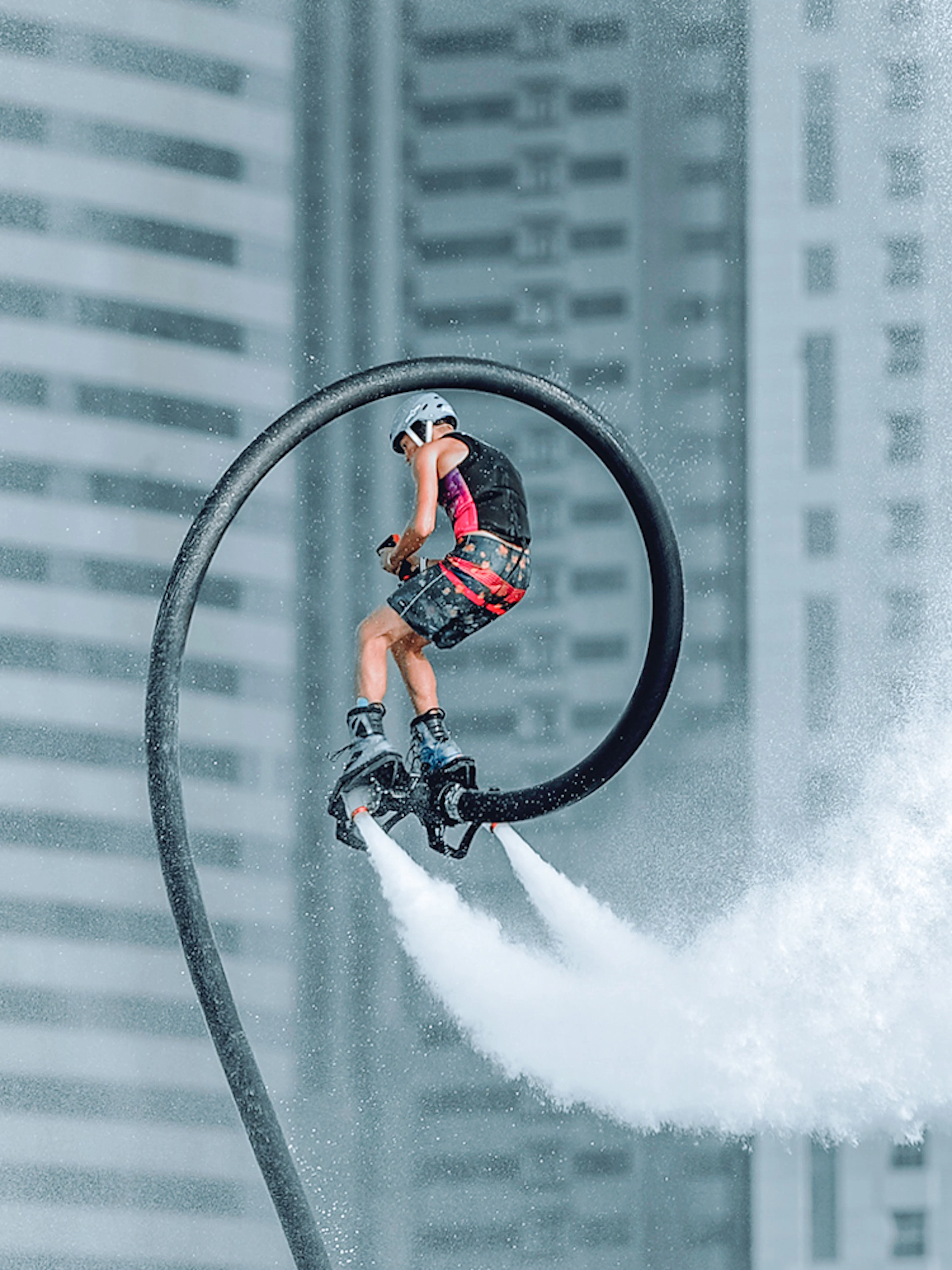 Person flyboarding with water jets in front of Dubai skyscrapers.