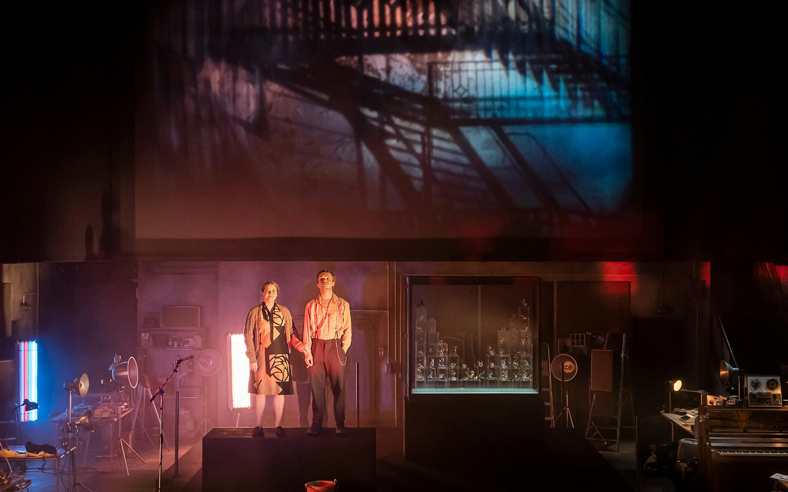 Two actors on stage during a performance of "The Glass Menagerie" with a staircase projection.