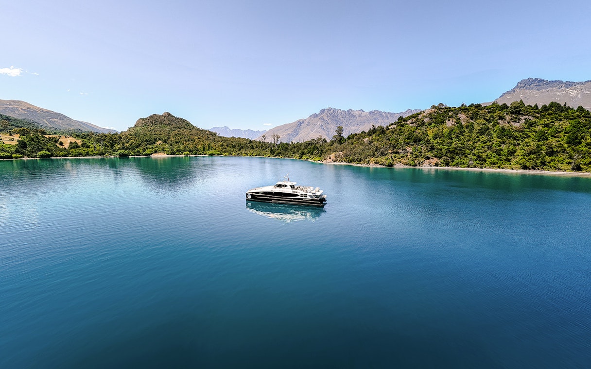 Boat cruising on Lake Wakatipu with mountainous landscape in the background.