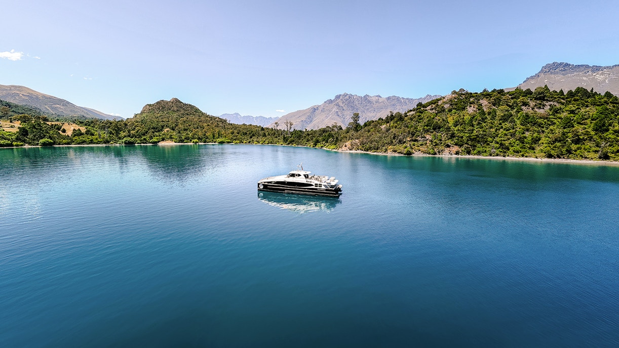 Boat cruising on Lake Wakatipu with mountainous landscape in the background.