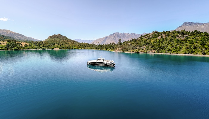 Boat cruising on Lake Wakatipu with mountainous landscape in the background.
